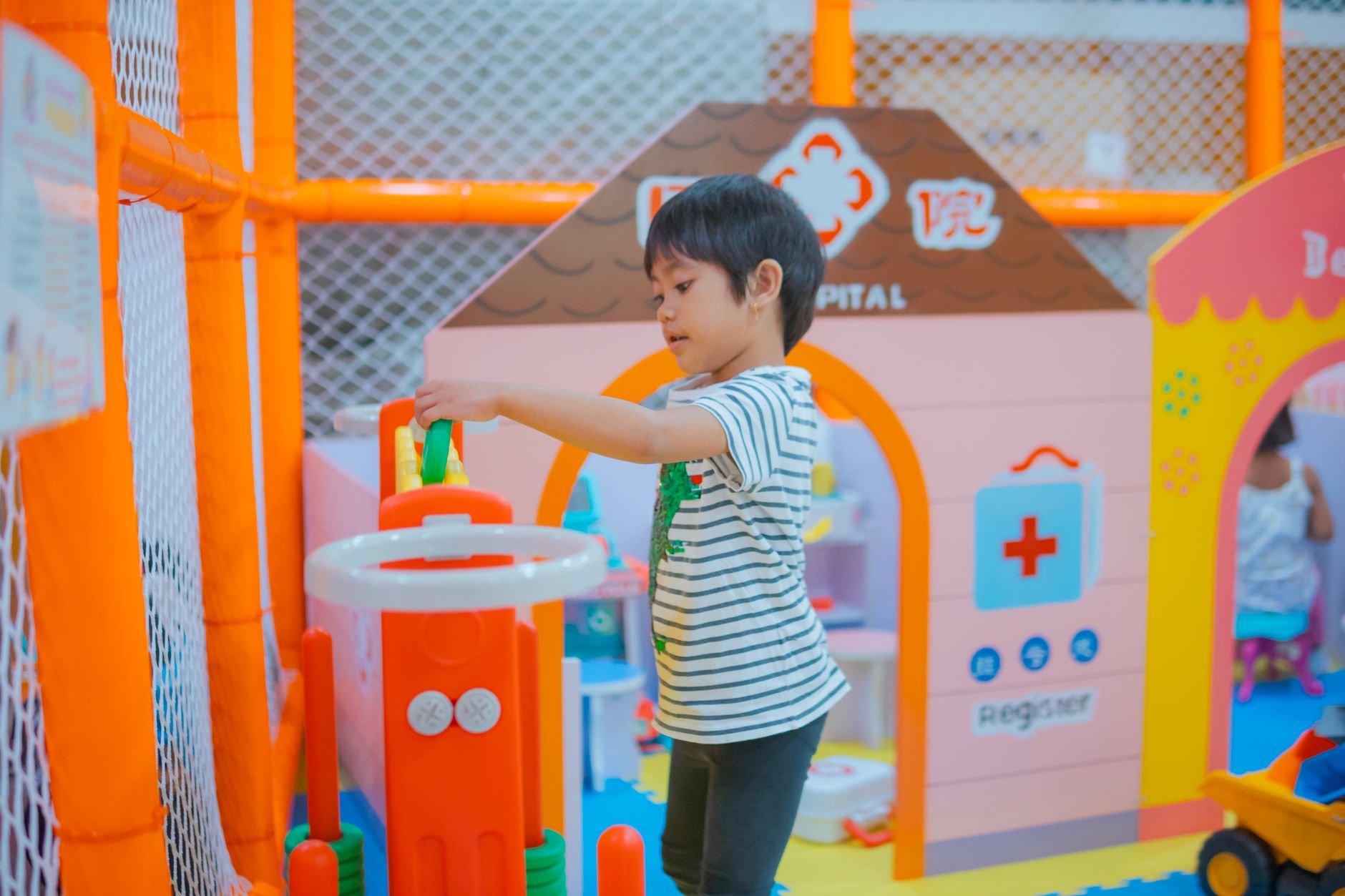 A child enjoys playtime in a colorful indoor playground with toys and structures.